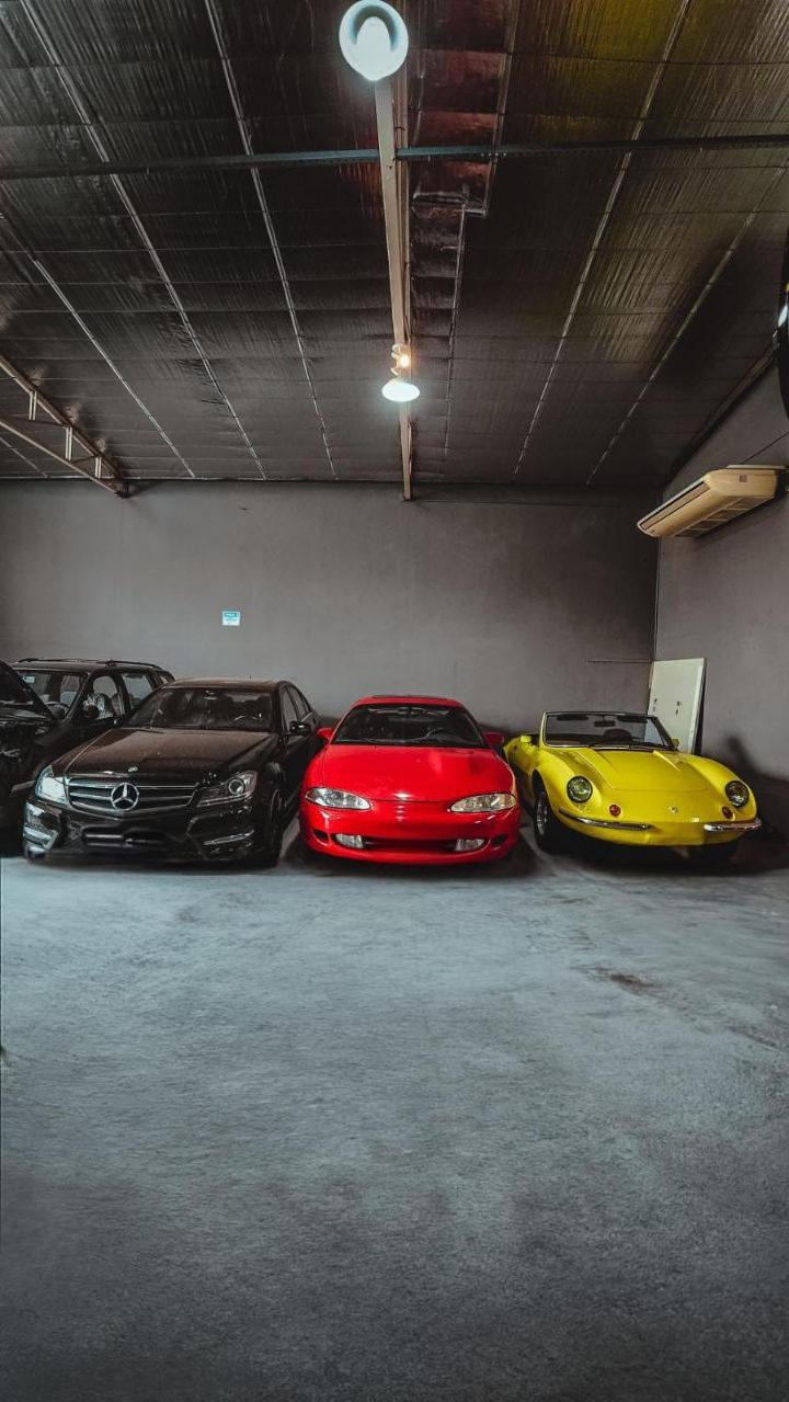 Mercedes, Mitsubishi Eclipse e um conversível amarelo estacionados na oficina